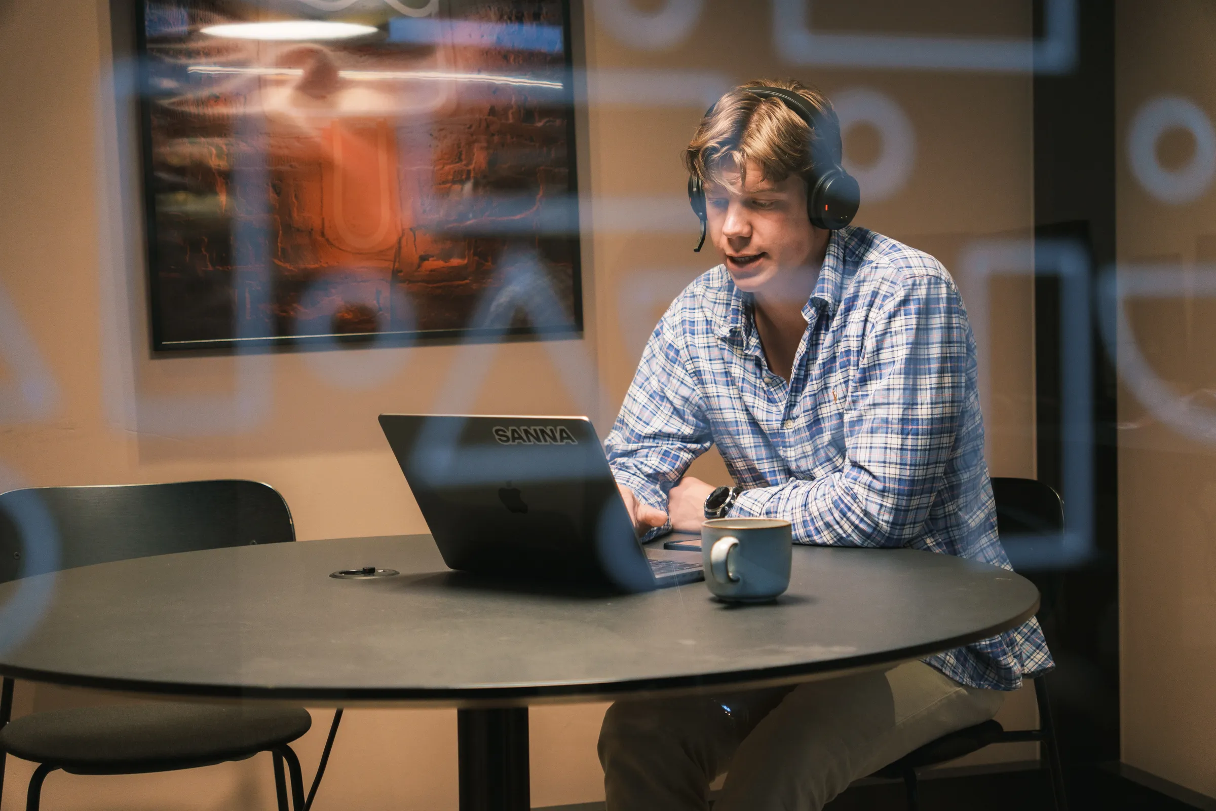 Medarbeider med headset ved laptopen i et glassmøterom